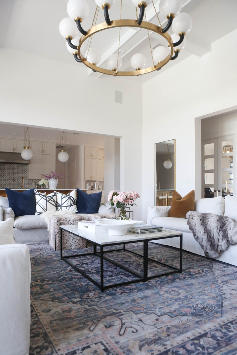 CC and MIke Living Remodel Reveal large natural wood island with quartz countertops and gold bar stools living room with navy rug slipcover crypton fabric navy Hathaway navy velvet pillows leopard ottomans marble coffee tables navy and pink large area rug