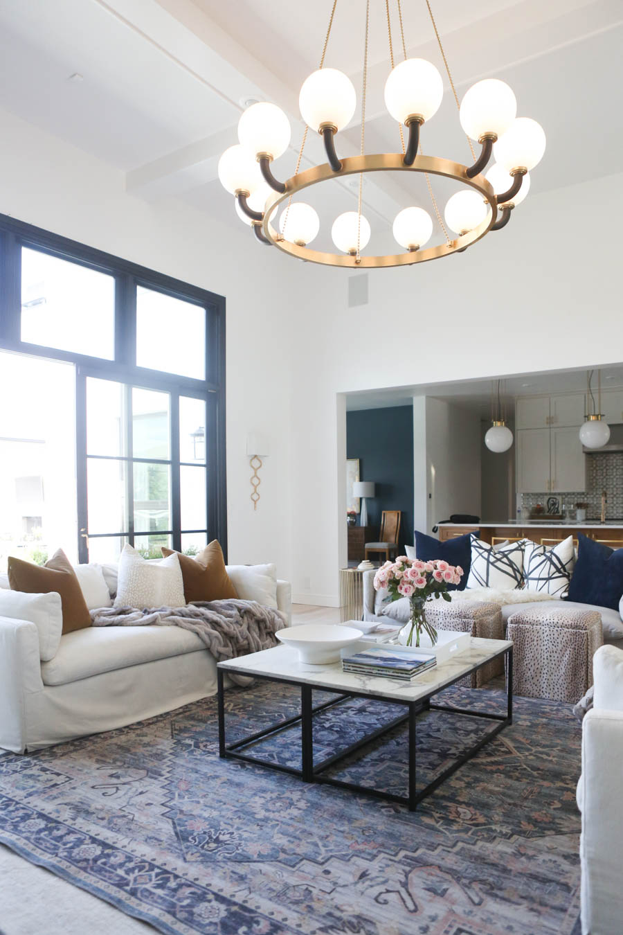 CC and MIke Living Remodel Reveal large natural wood island with quartz countertops and gold bar stools living room with navy rug slipcover crypton fabric navy Hathaway navy velvet pillows leopard ottomans marble coffee tables navy and pink large area rug