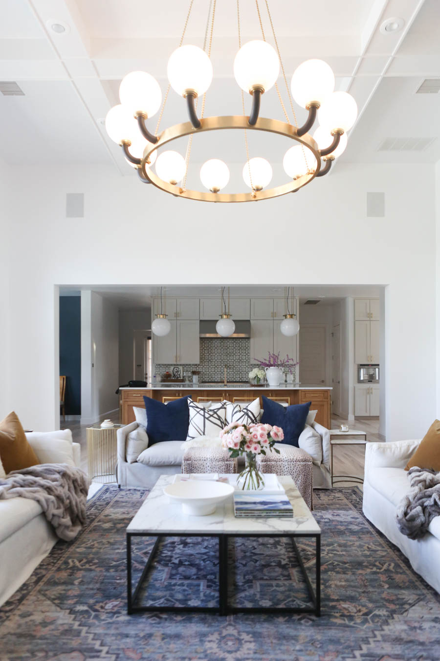 CC and MIke Living Remodel Reveal large natural wood island with quartz countertops and gold bar stools living room with navy rug slipcover crypton fabric navy Hathaway navy velvet pillows leopard ottomans marble coffee tables navy and pink large area rug