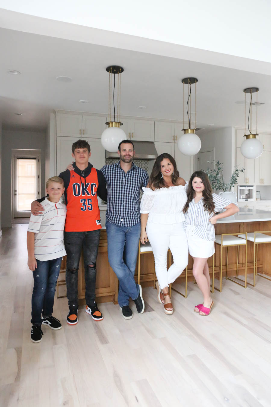 CC and MIke Kitchen Remodel Reveal large natural wood island with quartz countertops and gold bar stools black and gold pendants Ann sacks patterned backsplash gold Brizo faucet large Kallista stainless steel sink open floorpan