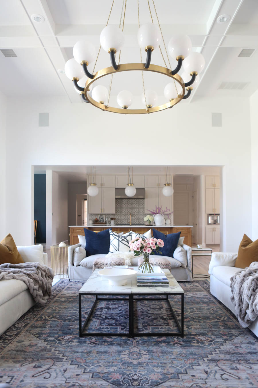 CC and MIke Living Remodel Reveal large natural wood island with quartz countertops and gold bar stools living room with navy rug slipcover crypton fabric navy Hathaway navy velvet pillows leopard ottomans marble coffee tables navy and pink large area rug