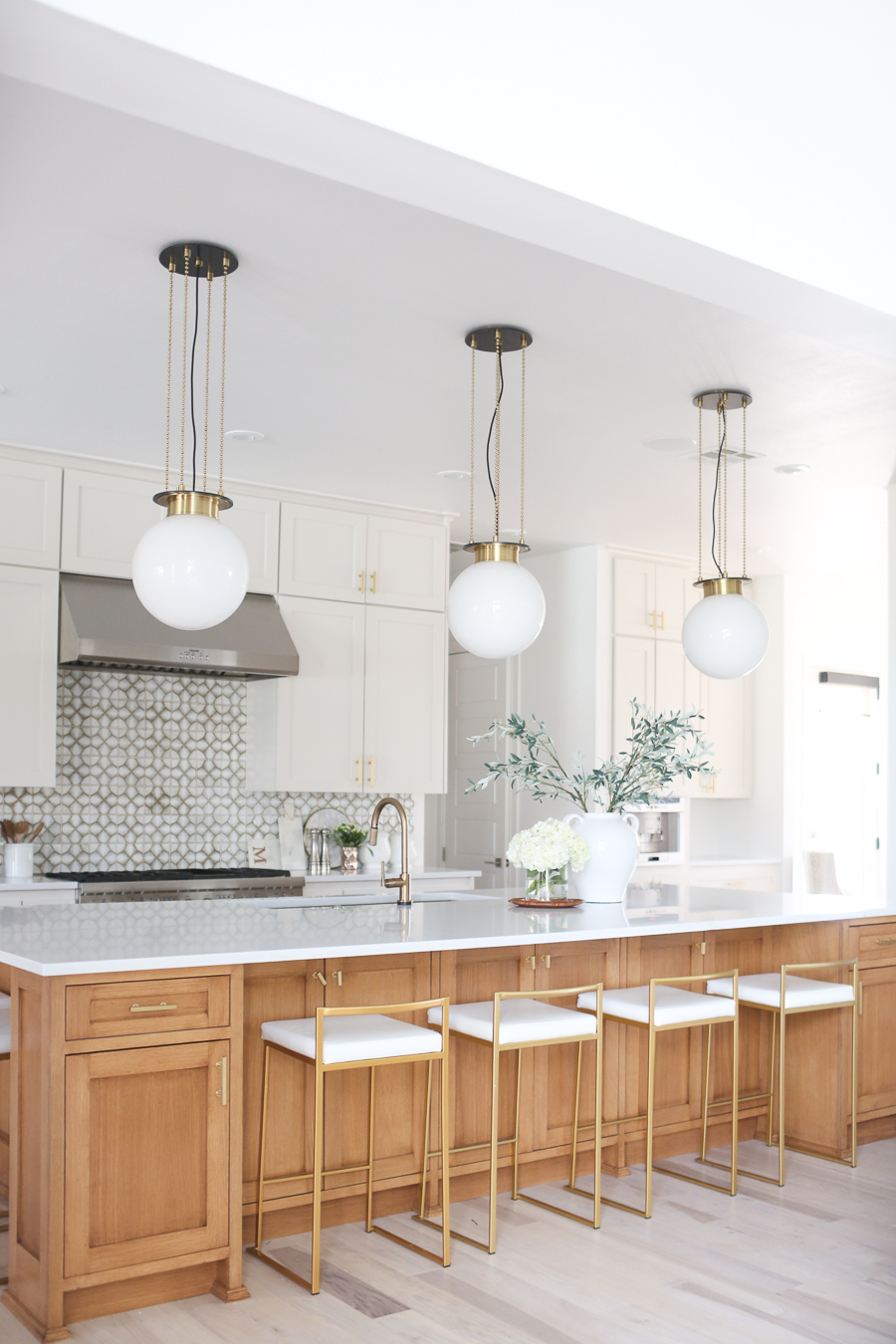 CC and MIke Kitchen Remodel Reveal large natural wood island with quartz countertops and gold bar stools black and gold pendants Ann sacks patterned backsplash gold Brizo faucet large Kallista stainless steel sink open floorpan