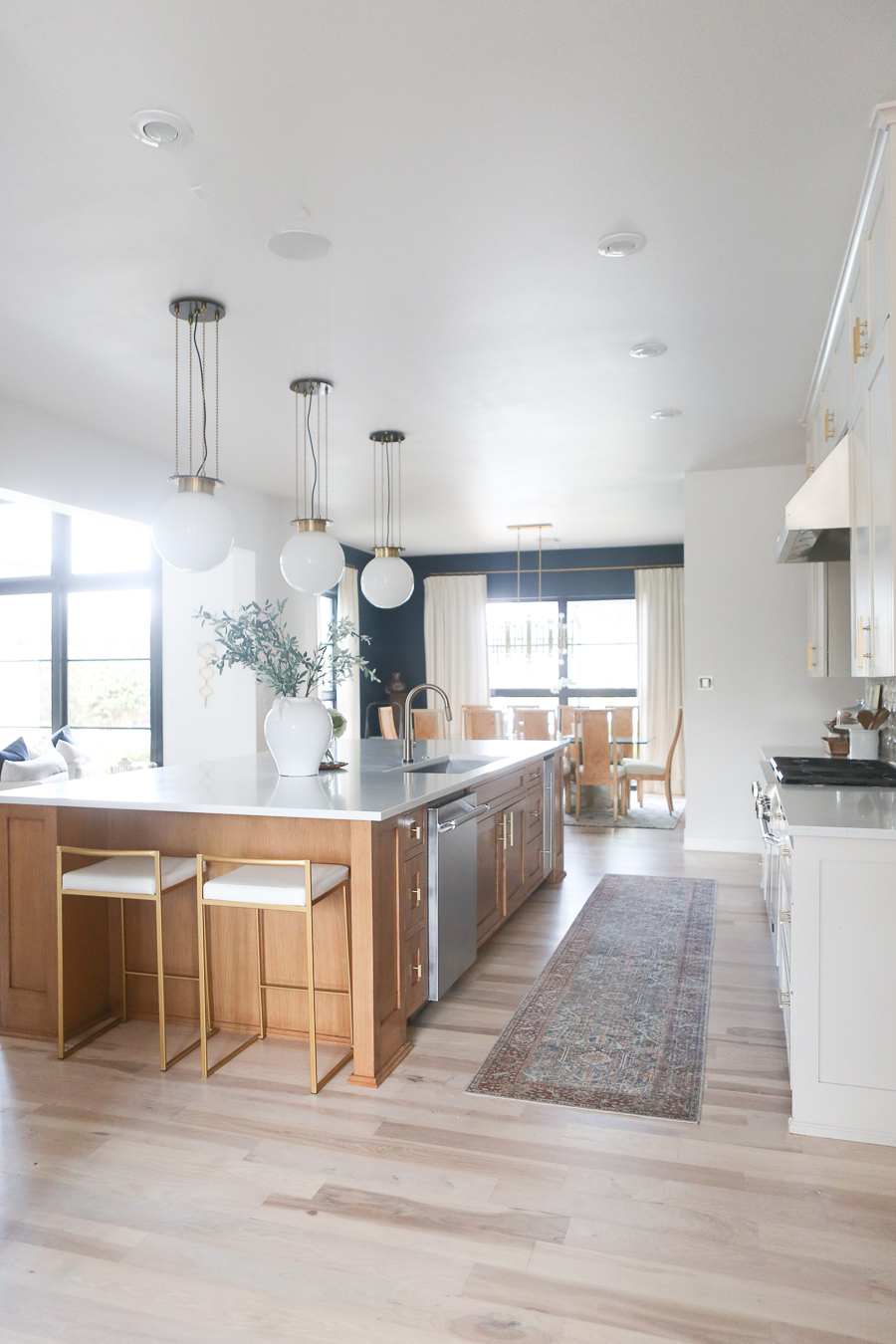 CC and MIke Kitchen Remodel Reveal large natural wood island with quartz countertops and gold bar stools black and gold pendants Ann sacks patterned backsplash gold Brizo faucet large Kallista stainless steel sink open floorpan