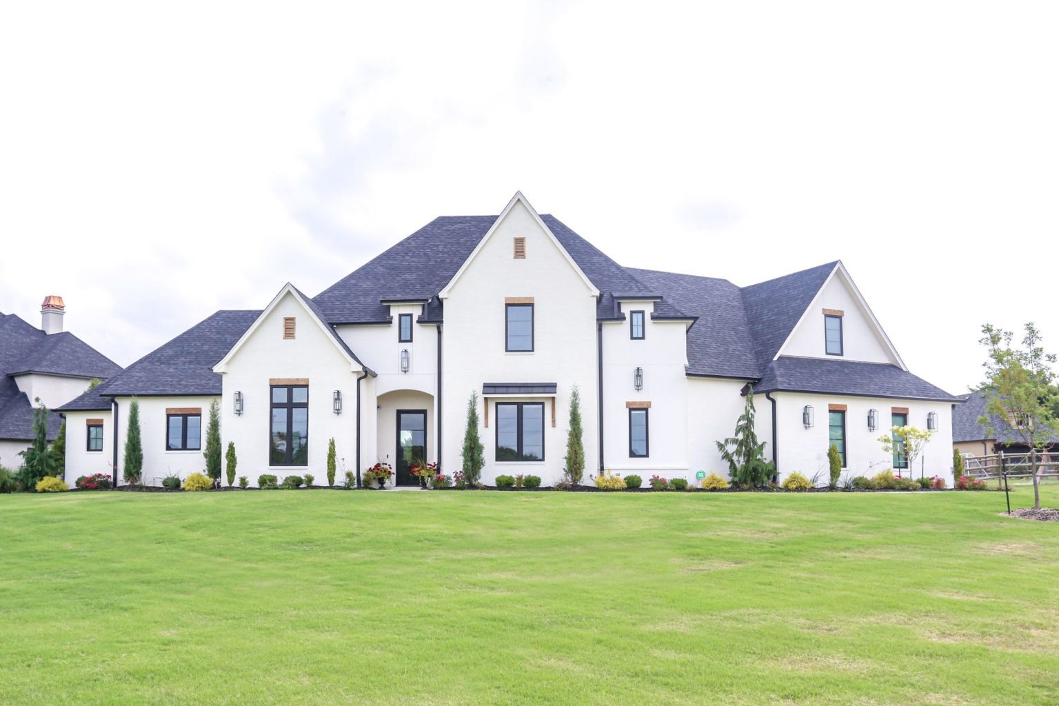 Front of the house at Meadowlark with a large green lawn, manicured landscaping, and a slurried brick exterior.